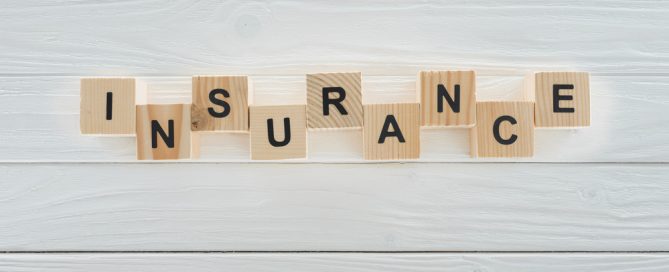 insurance spelled out with letter tiles on white wooden planks