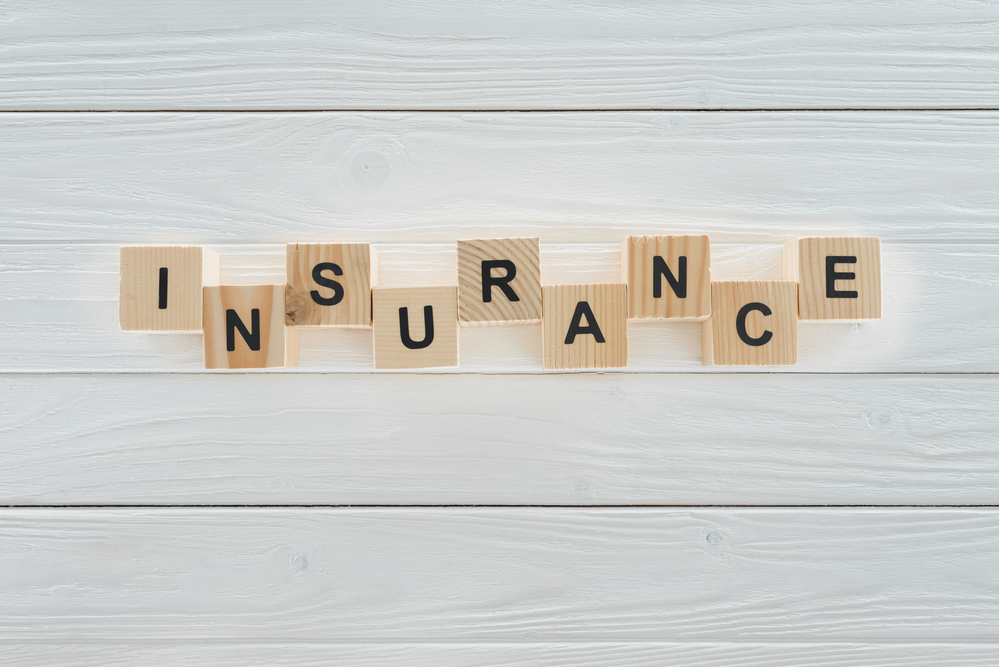 insurance spelled out with letter tiles on white wooden planks