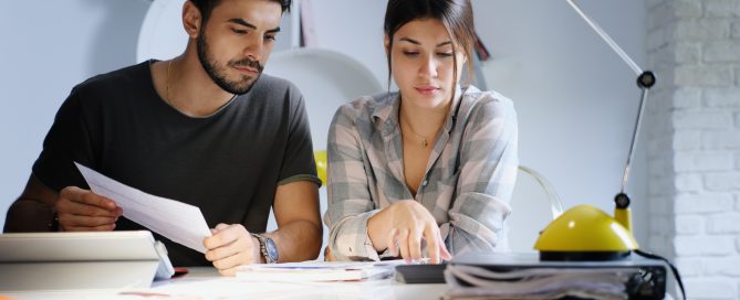 Young couple reviewing invoices and doing family business plan. Concept of money and economic problem for man and woman living together