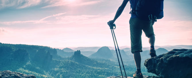 image of hiker at the top of a mountain looking onto a beautiful view